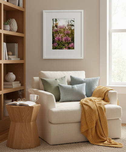 Cozy living room with a beige armchair, wooden side table, and floral artwork with a sunkissed bumblebee on the wall.
