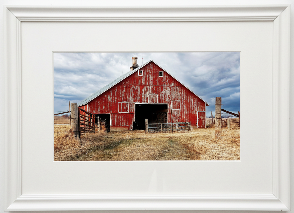 Red barn in an iowa farm field with a white frame