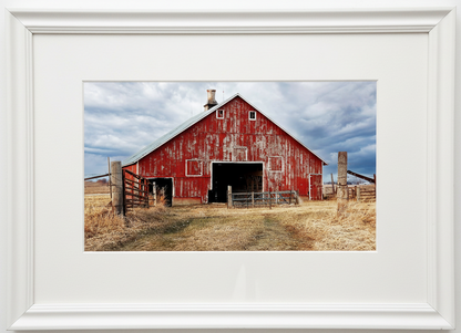 Red barn in an iowa farm field with a white frame