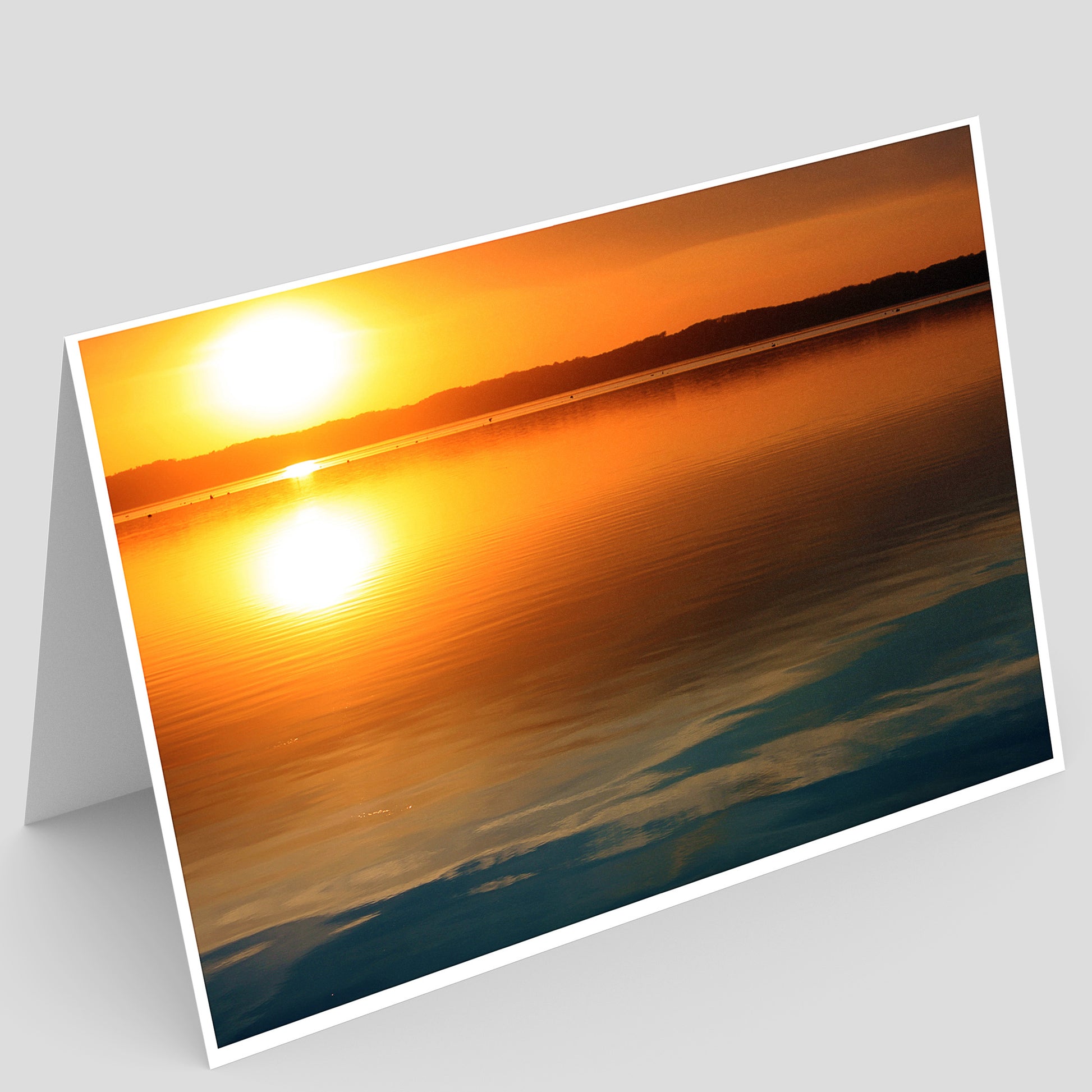 Orange Sunset reflecting over the blue waters of the mississippi river in Illinois with a white border on a gray background