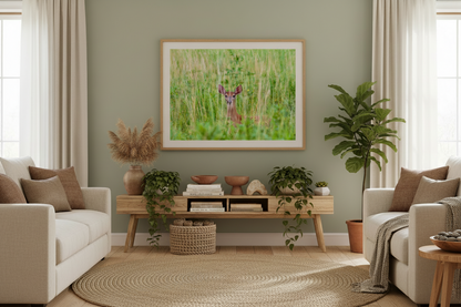Living room with a green wall, framed artwork of a deer fawn, and decorative plants.