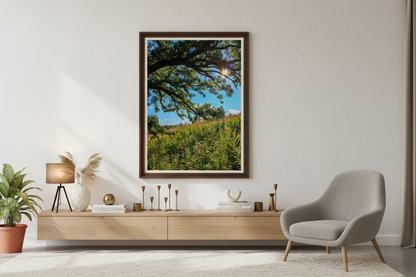 Modern living room with a large framed picture of a tree and prairie, a gray armchair, and a wooden console table.