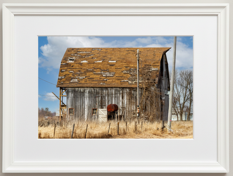 Framed photograph of an old wooden barn with a white frame.