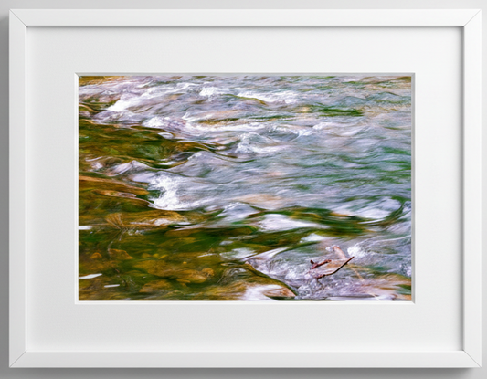 Framed artwork of flowing water in iowa with green and brown hues.