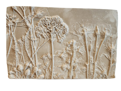 Front view of decorative wall art with bas relief floral design on a beige background.  