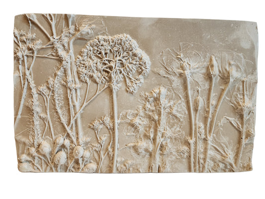 Front view of decorative wall art with bas relief floral design on a beige background.  
